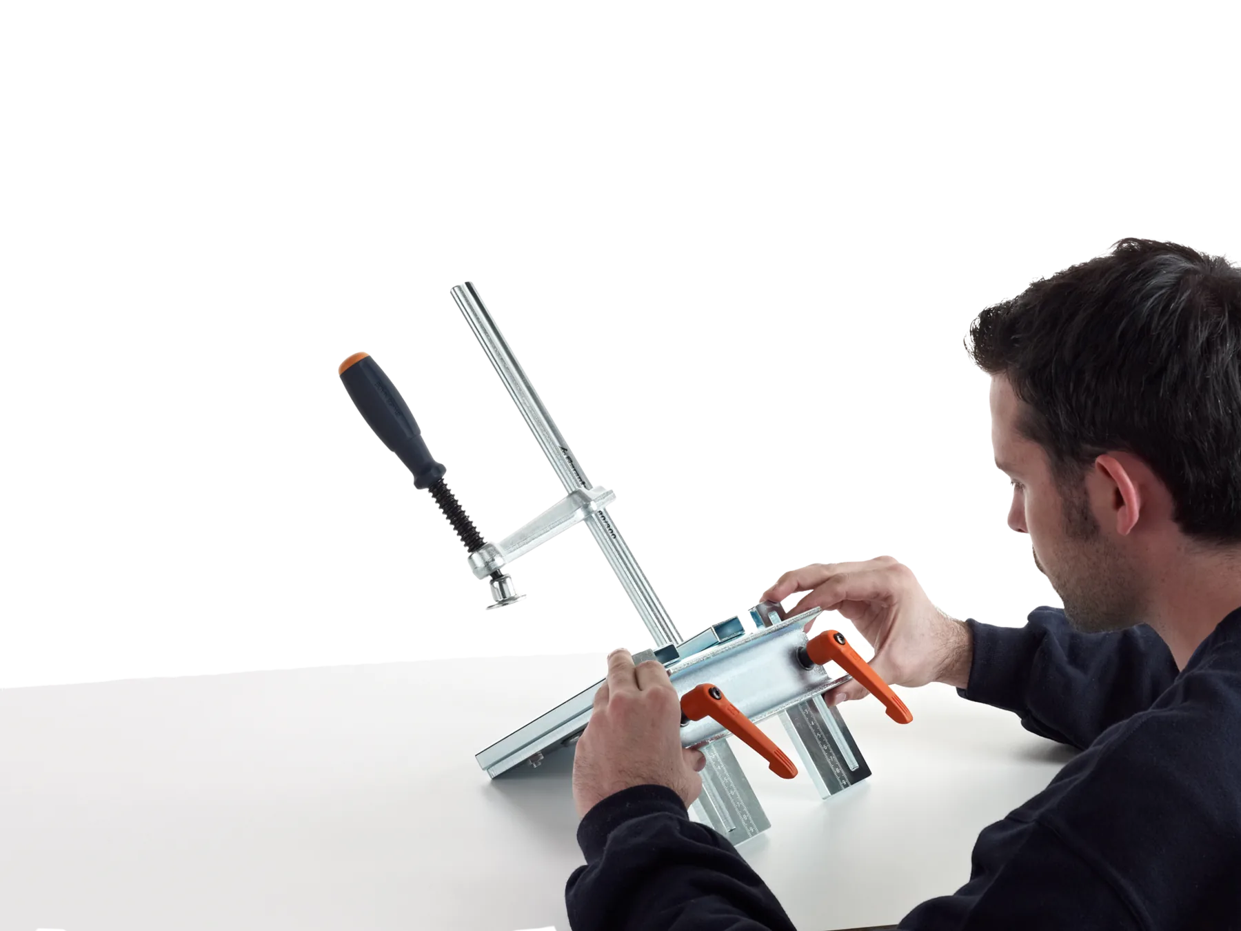 Metallbauer stellt die CREA-HEAVY am Arbeitstisch ein und löst dazu die beiden orangen Klemmhebel